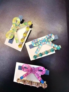 Détail des barrettes à nœuds rayés colorés et des clips perlés pour la coiffure