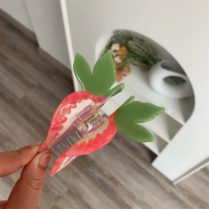 Detailed view of creative strawberry hair claw with pink marble texture and green leaf