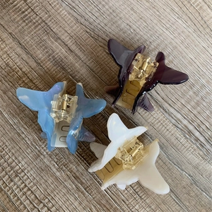 Detailed view of three butterfly hair clips in blue, purple, and white acetate resin
