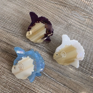 Detail view of cute sunfish hair clips in purple, cream and blue acetate on wood