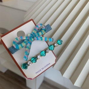 Détail d'un nœud à rayures bleues et d'une barrette dorée avec des gemmes