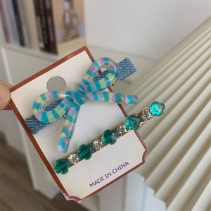 Détail d'un ensemble de barrette noeud et épingle à cheveux fleurie sur carte