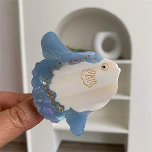 Detail of blue and white acetate sunfish hair claw clip with golden dot patterns