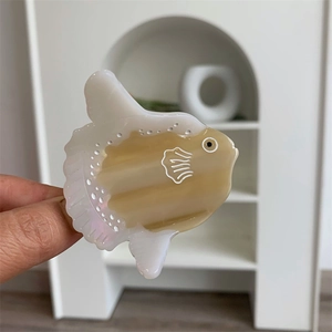 Detailed close-up of a cute sunfish hair claw clip made of glossy acetate material
