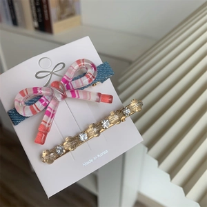 Ensemble de barrettes avec nœud rayé et strass sur carte de présentation blanche