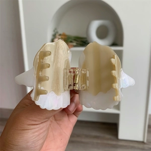 Detail of dual-tone acetate sunfish hair claw clip with pearlescent finish and metal spring