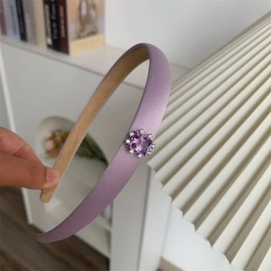 Gros plan d'un serre-tête en satin violet avec un ornement floral en zircon carré