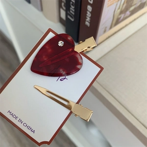 Detailed macro view of two tortoiseshell resin heart hair clips with golden metal base