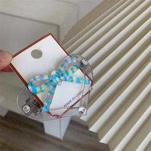Detail of candy color heart hair clip with striped bow and rhinestones on card