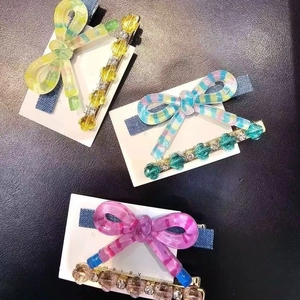 Trois lots de barrettes en acétate à rayures et perles colorées sur fond noir élégant