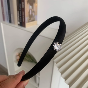 Détail d'un serre-tête fin en tissu noir orné de motifs en cristaux de zircon étincelants