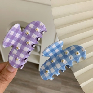 Dettaglio delle mollette per capelli in acetato con motivo a scacchi e piccoli fiori bianchi