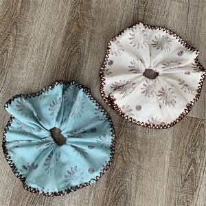 Nahaufnahme von übergroßen Baumwoll-Scrunchies mit Sonnenmuster und Zickzack-Stichen