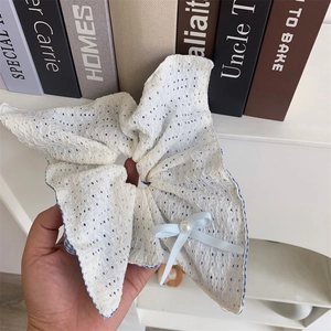Detail of blue plaid bow hair scrunchie with white embroidery and pearl decoration