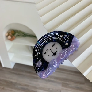 Detail shot of celestial acetate hair claw clip with star and moon face patterns