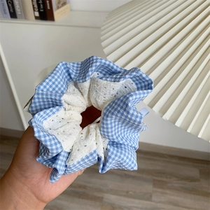 Blue and white checkered scrunchie with lace trim detail shown in a cozy home setting