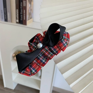 Detail of red plaid fabric and black silk bow hair claw clip with a white imitation pearl