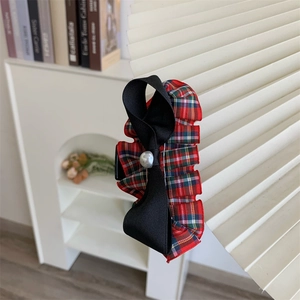 Detailed shot of red plaid hair claw with black ribbon bow and elegant faux pearl