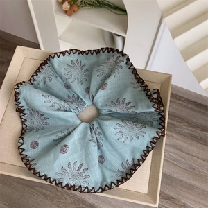 Übergroßer hellblauer Haargummi mit violettem Blumendruck und braunem Häkelrand