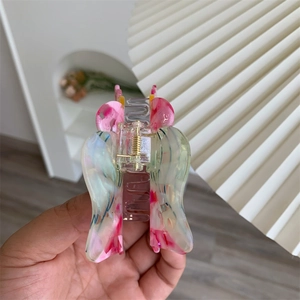 Close-up of butterfly shell claw clip with pink and green colorful acetate patterns