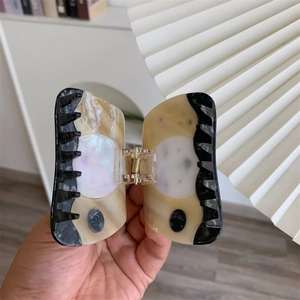 Close-up detail of acetic acid sun goddess hair claw with marble texture finish