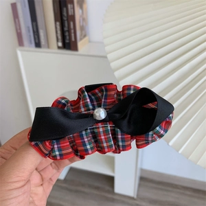 Vintage red plaid bow hair claw clip with satin ribbon and pearl detail held in hand