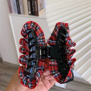 Detail of red and green plaid fabric hair claw clip with vintage British style texture