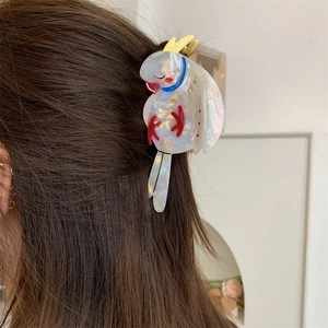 Detail of a bird-shaped acetate hair claw clip worn on long dark brown hair
