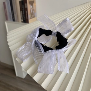 Close-up of elegant black elastic hair tie with multiple white translucent lace bows