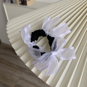 Detail of sweet black hair scrunchie with delicate white lace bows for elegant hairstyles