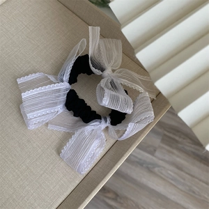Close-up of white organza bow hair scrunchies on a minimalist beige background