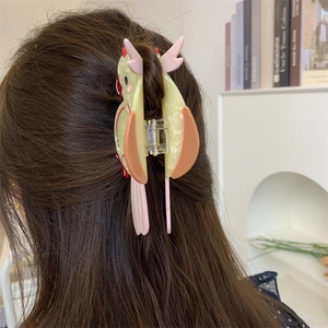 Detailed back view of a colorful parrot acetate hair claw clip worn on long hair
