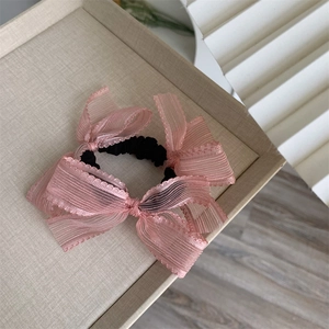 Close-up of pink mesh bow scrunchie with layered fabric texture and elastic band