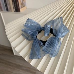 Detailed view of blue striped mesh scrunchie with layered bow on a display stand