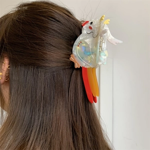 Detail of creative acetate rooster hair claw clip on dark brown hair with pearl finish