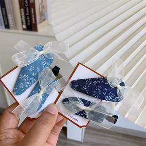 Floral print hair clips with white organza bow accents on a display card