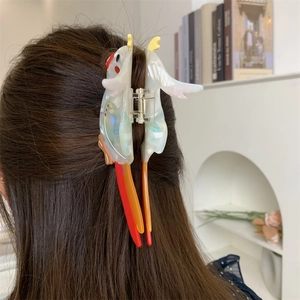 Macro detail of parrot-shaped acetate hair claw clip worn on dark brown straight hair