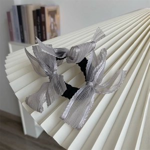 Set of two elegant grey pleated ribbon bow hair ties on a stylish white display stand
