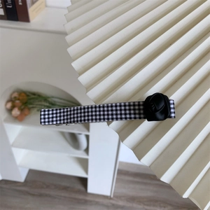 Détail d'une fleur de rose noire sur une barrette en tissu à carreaux noir et blanc