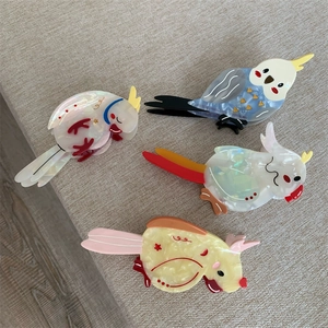 Detailed macro view of acetate parrot hair claw clips with colorful bird pattern textures