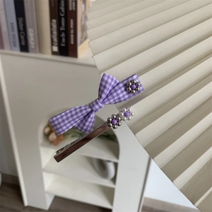 Dettaglio della clip per capelli a fiocco viola a scacchi e spilla con perle floreali