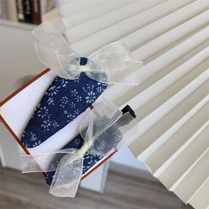 Detailed shot of two blue floral hair clips featuring delicate organza bows on card