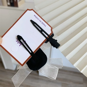 Detail of elegant cream organza bow hair clip with black velvet center on card