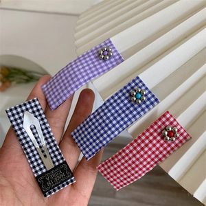 Set of four checkered fabric BB hair clips with metal flowers and color beads in a hand