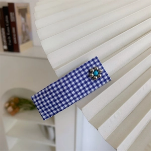Detailed close-up of blue gingham fabric hair clip with a silver bead flower decoration