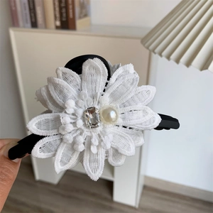 Détail de la pince à cheveux marguerite en dentelle blanche avec perle et strass