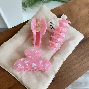 Détail des pinces à cheveux en acétate rose avec décorations de fleurs en perles