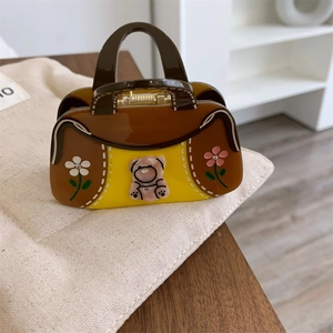 Détail de la pince à cheveux en acétate en forme de sac avec ours rose et fleurs