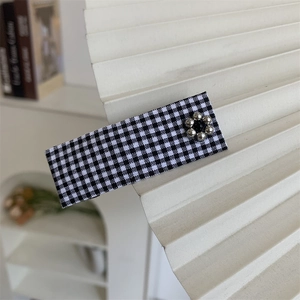 Detail of a black and white checkered hair clip with a silver metallic bead flower