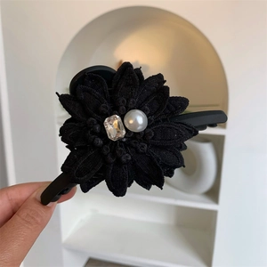Détail d'une grande pince à cheveux fleur noire avec cristal et perle pour cheveux longs